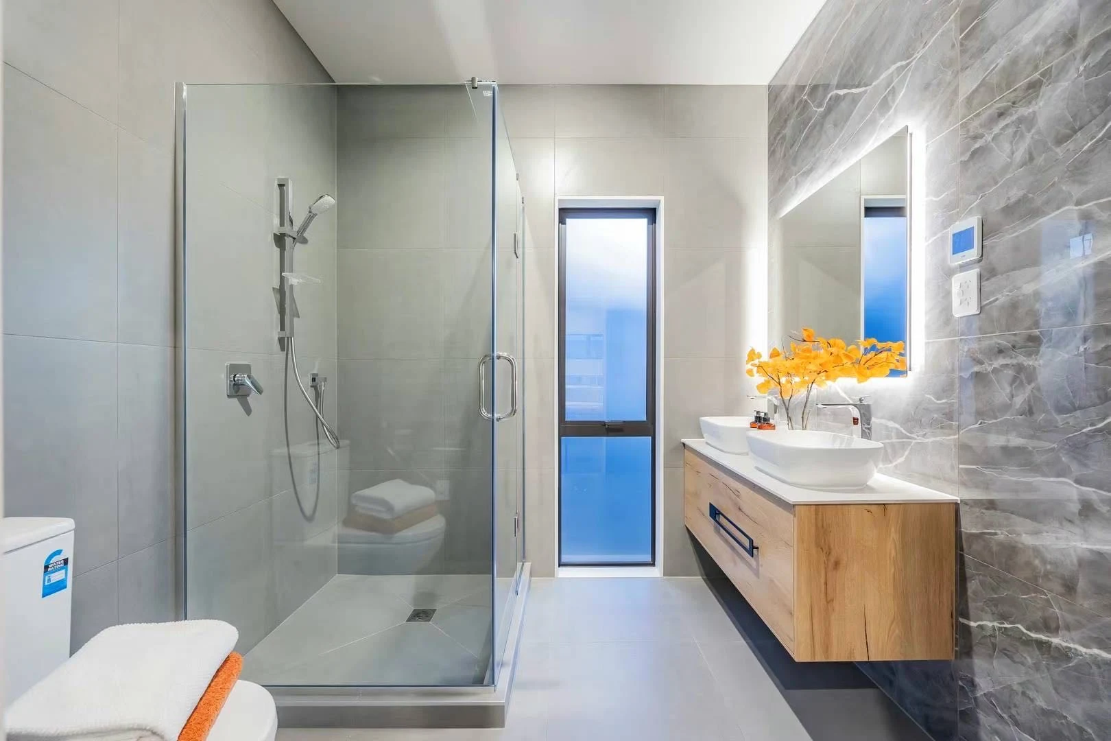 Grey veined feature wall beside a timber vanity and illuminated mirror